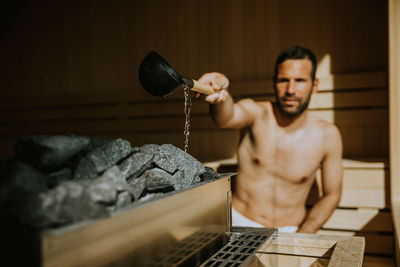 Mann mit Handtuch macht Aufguss in Sauna