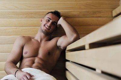 Junger Mann mit argen Muskeln sitzt in Sauna