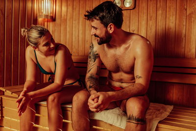 Frau im Bikini und tätowierter Mann schwitzen in Sauna