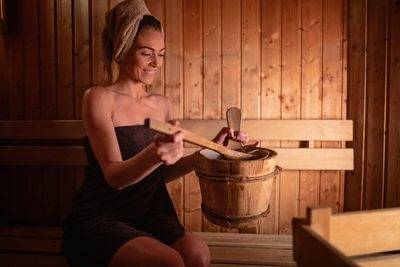 Frau mit Handtuch macht Aufguss in Sauna