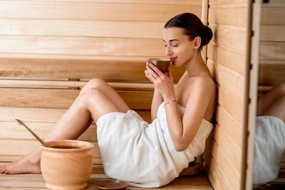 Braunhaarige Frau trinkt Tee in Sauna
